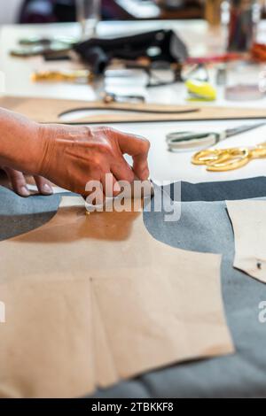 Stilista che sfoggia motivi di moda con un gesso sartoriale. Shot verticale. Foto Stock