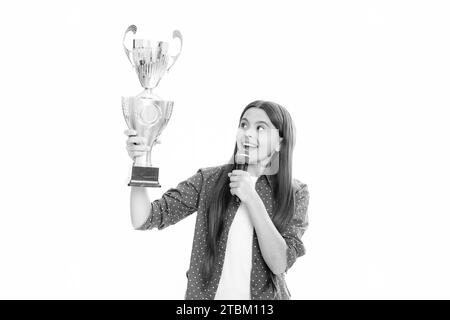 Ragazza adolescente in possesso di un trofeo microfono discorso. Il bambino vincitore ha vinto il concorso, celebrando il successo e la vittoria, il premio di successo. Foto Stock