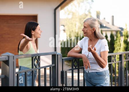 Vicini emotivi che discutono vicino alla recinzione all'aperto Foto Stock