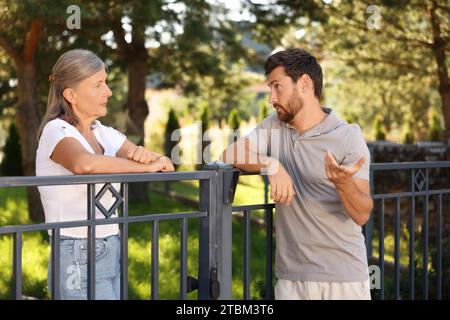 Vicini emotivi che discutono vicino alla recinzione all'aperto Foto Stock