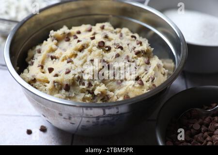 Impasto di biscotti con scaglie di cioccolato in una ciotola sul tavolo, primo piano Foto Stock