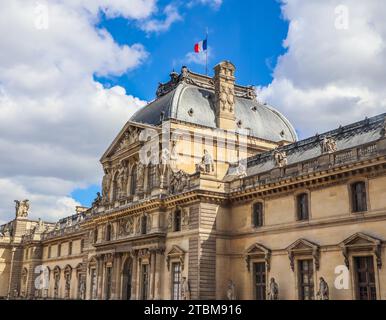 Francia, 04 aprile 2019: Dettagli architettonici della facciata del Louvre a Parigi con la bandiera francese sul tetto Foto Stock