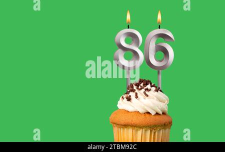 Biglietto di compleanno con numero di candela 86 - Cupcake su sfondo verde Foto Stock