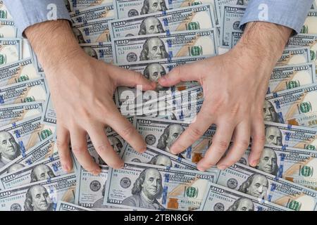 L'uomo ruba denaro, uomo nel business vestiti con dollari, Contanti in mani. Profitti, risparmio. Pila di dollari. Successo, motivazione, flussi finanziari, ricchezza. Foto Stock