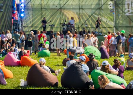 Scena di festival all'aperto con il pubblico che si rilassa su sacchetti di fagioli colorati, godendosi uno spettacolo dal vivo. Foto Stock