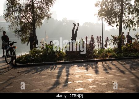 La gente del posto si allena alle rive del lago Hoan Kiem ad Hanoi il venerdì presto come parte della loro routine di allenamento. Molti residenti della capitale del Vietnam ballano e si esercitano sulle rive dei laghi della città all'alba. Data immagine: Venerdì 8 dicembre 2023. Foto Stock