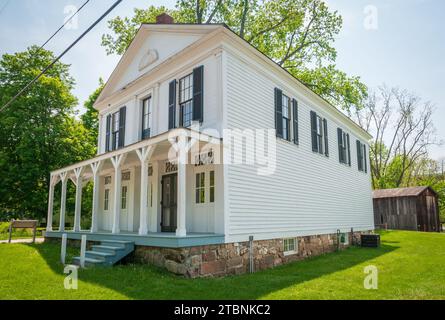 Un edificio bianco a due piani in assicelle con un lungo portico colonnato e persiane nere si erge su un prato nel Cuyahoga Valley National Park, Ohio. Foto Stock