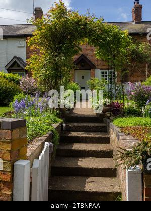 Aprire il cancello anteriore con gradini e sentiero che conduce attraverso un porticciolo a un vecchio cottage, Abthorpe Village, Northamptonshire, Regno Unito Foto Stock