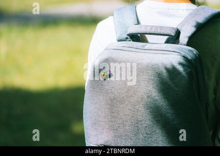 Ragazzo adolescente con zaino grigio con simbolo dell'arcobaleno infinito autismo. Giornata mondiale di sensibilizzazione all'autismo, movimento per i diritti dell'autismo, neurodiversità, autismo Foto Stock