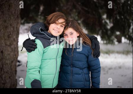 Ritratto sorridente di fratelli in giacche invernali all'aperto sulla neve Foto Stock