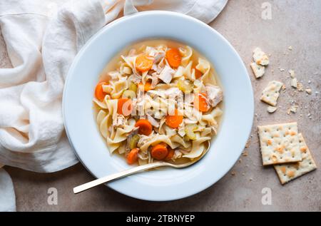 Primo piano della zuppa di spaghetti di pollo in un recipiente bianco su sfondo beige. Foto Stock