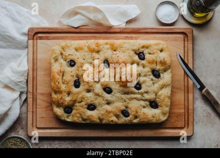 Focaccia di olive e rosmarino appena sfornata su tavola di legno. Foto Stock
