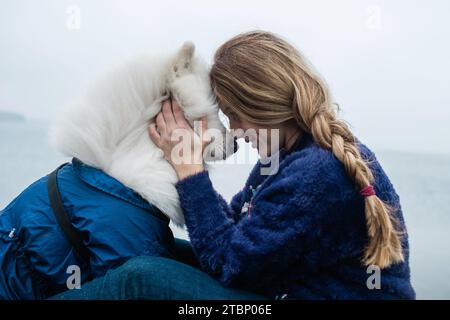 La ragazza cammina con un cane Samoyed bianco e soffice in natura Foto Stock