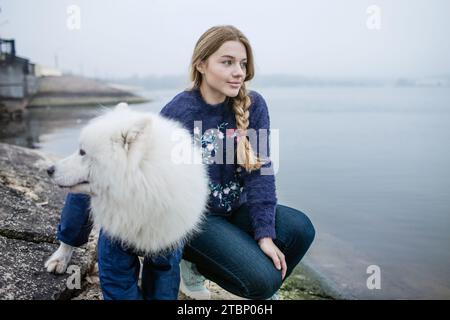 La ragazza cammina con un cane Samoyed bianco e soffice in natura Foto Stock