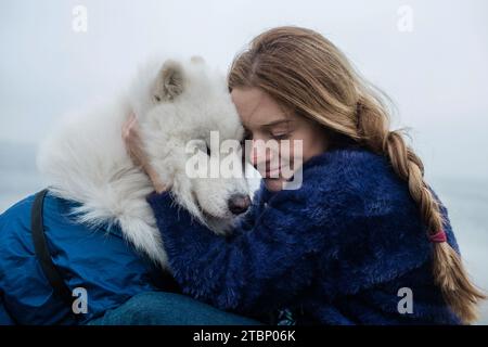 La ragazza cammina con un cane Samoyed bianco e soffice in natura Foto Stock