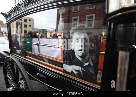 La processione funebre di Shane MacGowan si fa strada per le strade di Dublino prima del suo funerale nella Co Tipperary. Il cantautore, che ha trovato fama come cantante principale della band punk/folk londinese The Pogues, è morto all'età di 65 anni la settimana scorsa. Data immagine: Venerdì 8 dicembre 2023. Foto Stock