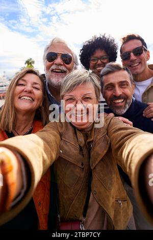 Gruppo multirazziale di persone mature che scattano un selfie insieme durante il viaggio con la famiglia e gli amici. Foto Stock