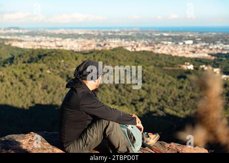 L'uomo di mezza età contempla i paesaggi del Parco naturale Garraf mentre riposa in cima alla montagna. Foto Stock
