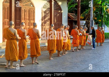 Lampang, Thailandia - 2 dicembre 2023: Monaci buddisti thailandesi Theravada che camminano per le elemosine mattutine a Nakhon Lampang, Thailandia. Foto Stock