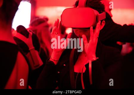 Avvolto da un bagliore cremisi, una donna si immerge in un mondo virtuale, esplorando le frontiere della tecnologia e deliziandosi con un evento di luce rossa di digi Foto Stock