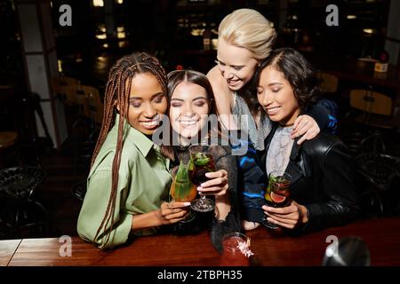 allegri amici multiculturali che bevono bicchieri da cocktail e sorridono a occhi chiusi al bar Foto Stock