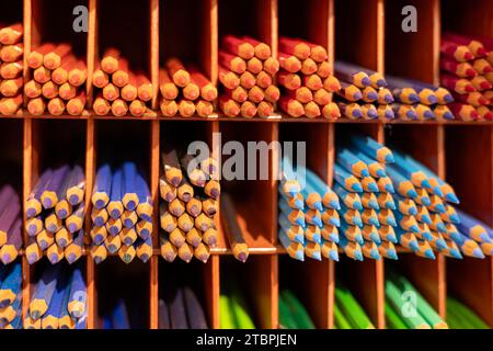 Le matite colorate disposte in una pila ordinata su uno scaffale Foto Stock