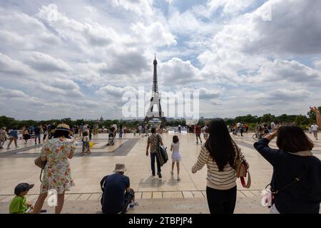 Un gruppo di persone che passeggia lungo un marciapiede di fronte all'iconica Torre Eiffel a Parigi, in Francia Foto Stock