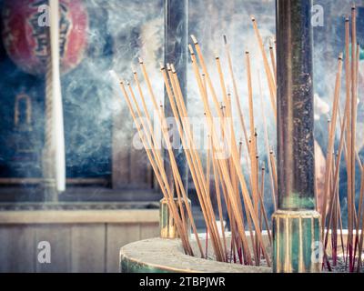 Un assortimento di bastoncini d'incenso con fumo profumato che si estrae da loro, esposti su uno sfondo bianco Foto Stock