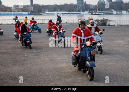 I membri del club di scooter Vespa RheinSchalter Koeln vestiti come Santas si riuniscono sul Deutzer Werft prima di un giro attraverso la città, Colonia, Germania. La Foto Stock