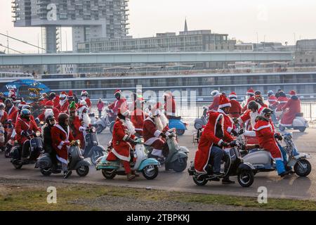 I membri del club di scooter Vespa RheinSchalter Koeln vestiti come Santas si riuniscono sul Deutzer Werft prima di un giro attraverso la città, Colonia, Germania. La Foto Stock