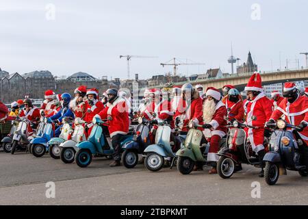 I membri del club di scooter Vespa RheinSchalter Koeln vestiti come Santas si riuniscono sul Deutzer Werft prima di un giro attraverso la città, Colonia, Germania. La Foto Stock