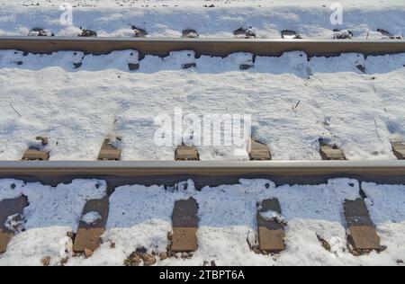 Un dettagliato primo piano dei binari innevati che evidenziano il contrasto tra i binari in acciaio e la neve bianca di Dugo Selo. Foto Stock