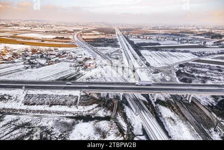 Strade intersecanti in un campo innevato vicino a Krizevci, Croazia, viste dall'alto, evidenziando il contrasto tra natura e infrastrutture. Foto Stock