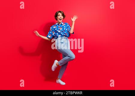 Foto del corpo di una bella e pazza ragazza con stampa blu, la camicia di babbo natale, la festa del capodanno 2024, isolata su sfondo di colore rosso Foto Stock