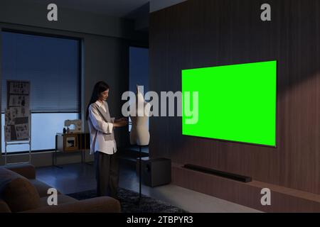 Le persone guardano e si divertono accanto al televisore, monitor con schermo verde Foto Stock