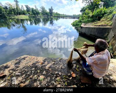 Un pescatore che pesca con la rete da pesca nel remoto villaggio del bengala occidentale in India Foto Stock
