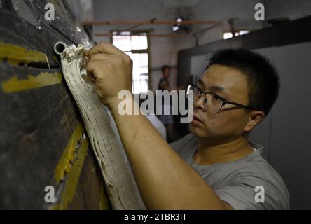 (231208) -- JINGXIAN, 8 dicembre 2023 (Xinhua) -- Wu fan asciuga la carta in un laboratorio di carta Xuan nella contea di Jingxian, nella provincia di Anhui della Cina orientale, 7 dicembre 2023. La carta Xuan, un tipo di carta fatta a mano, era originariamente prodotta nell'antica Cina e utilizzata sia per calligrafia cinese che per dipinti. La procedura di creazione della carta di Xuan è stata elencata come patrimonio culturale immateriale mondiale dall'UNESCO nel 2009. Jingxian, una contea sotto la città di Xuancheng nella provincia di Anhui, è il luogo in cui è stata inventata la carta Xuan. Guan Jiaming, responsabile del processo di stampaggio della carta in un laboratorio di carta Xuan, ha un pr Foto Stock