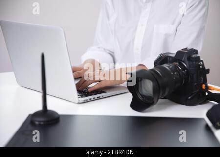 Fotografa, blogger che rivede le foto scattate con la sua fotocamera utilizzando un notebook Foto Stock