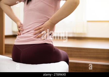 Una donna seduta su un letto e che la tiene in braccio con la mano Foto Stock