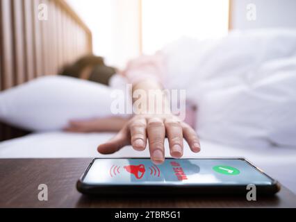 Una donna che indossa un occhiale cerca di toccare il suo smartphone mentre si sveglia dal sonno Foto Stock