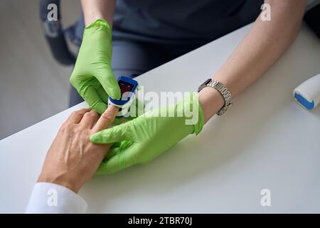 Medico esperto che misura il livello di saturazione dell'ossigeno nel sangue in una persona adulta Foto Stock