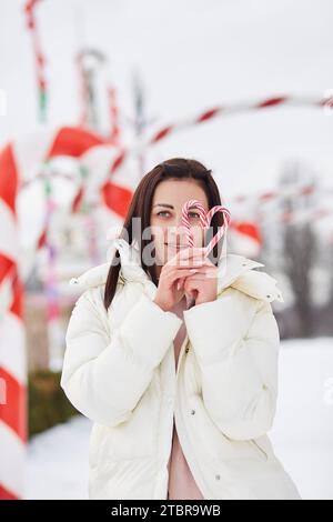 La donna tiene i bastoncini di caramello estetici natalizi. cuore in forma. Foto Stock