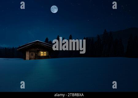 Capanna da sci con finestra illuminata in una fredda notte d'inverno Foto Stock