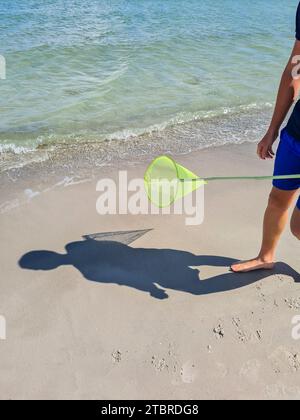 Germania, Meclemburgo-Pomerania Occidentale, penisola Fischland-Darß-Zingst, località di villeggiatura Prerow, rete da sbarco gialla sulla spiaggia con l'ombra di un ragazzo Foto Stock