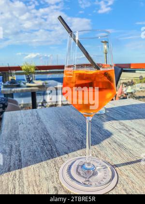 Una bevanda alcolica estiva Aperol Spritz di fronte al cielo blu con nuvole bianche su un tavolo in un ristorante, Prerow, Fischland-Darß-Zingst penisola, Meclemburgo-Vorpommern, Germania Foto Stock