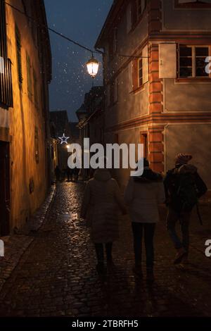 Gente che cammina attraverso un vicolo illuminato a Riquewihr, Francia, Alsazia Foto Stock