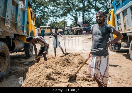 Operai che sparavano sabbia sui camion a Jaflong, Bangladesh. Foto Stock