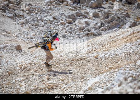 Italia, Dolomiti, ciclista alpinista su un sentiero alpino che porta la mountain bike sulle spalle in un tratto molto difficile Foto Stock