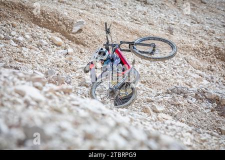 Italia, Dolomiti, ciclista alpinista su un sentiero alpino che porta la mountain bike sulle spalle in un tratto molto difficile Foto Stock