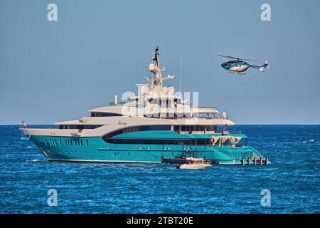 85 metri di sole al superyacht all'ancora con l'elicottero in arrivo per atterrare sull'eliporto. Foto Stock